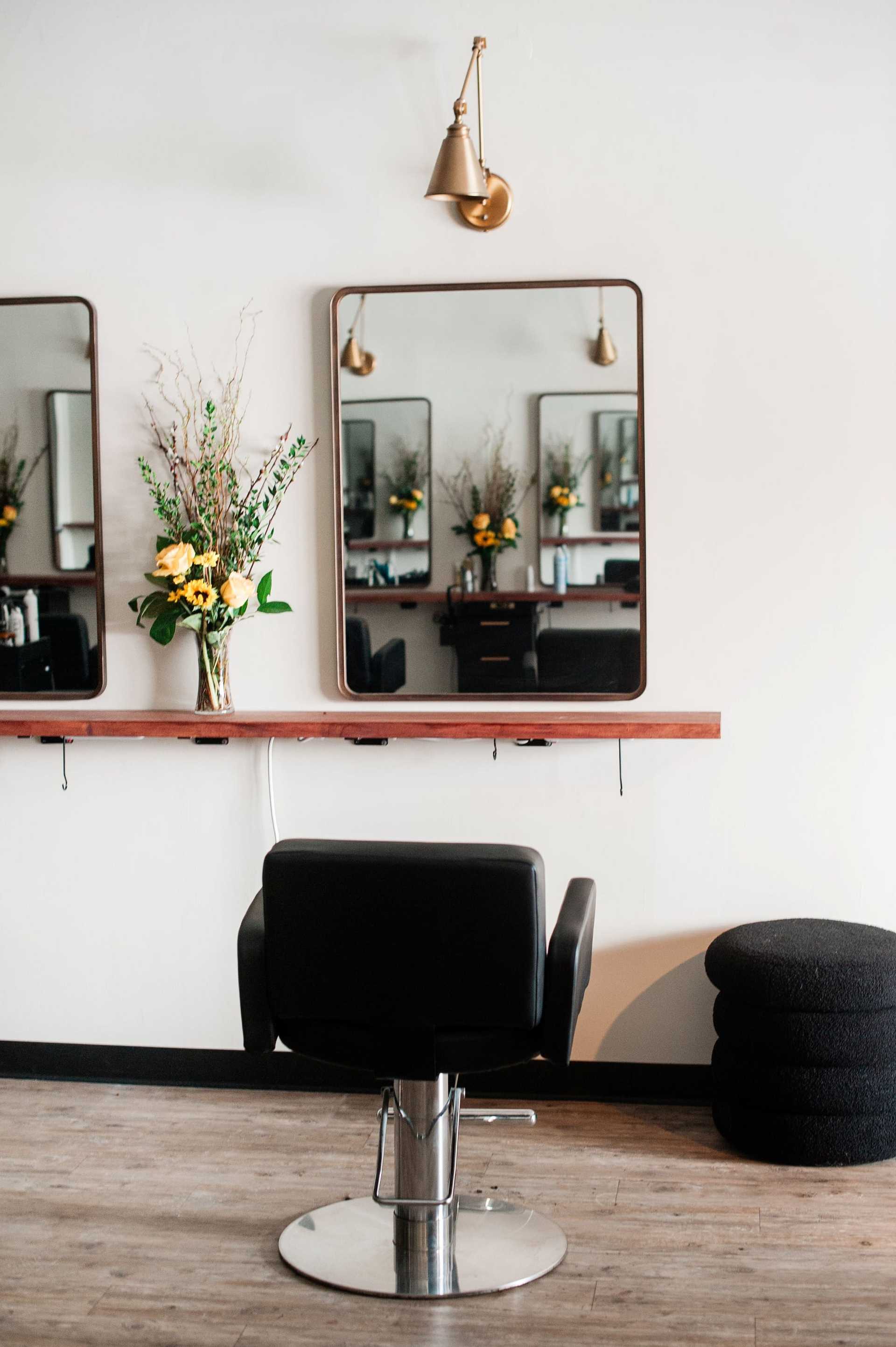 Modern salon setup with a single hair styling station, mirror, and fresh floral arrangement.